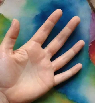 Una mano coloca suavemente su palma sobre una roca vibrante y multifacética